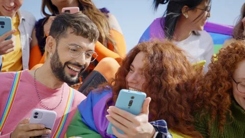 Large multiracial group young friends using cell phones outdoors. LGBT diverse Stock Footage 251467337
