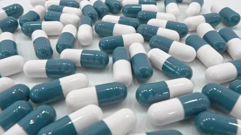 A large number of blue and white capsules scattered on a clean white surface Stock Footage 341032693