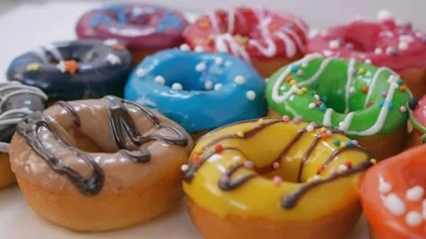 A large number of donuts with fruit glaze in different colors are displayed on Stock Footage 148519509