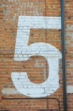 A large number five painted in white on a red brick wall Fotos Stock