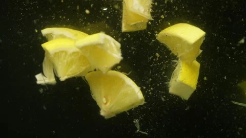 A large number of small pieces of lemon fall into the water. Stock Footage 264581012