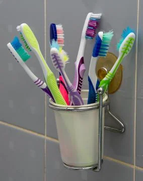 A large number of toothbrushes in a Cup attached to the wall in the bathroom Stock Photos