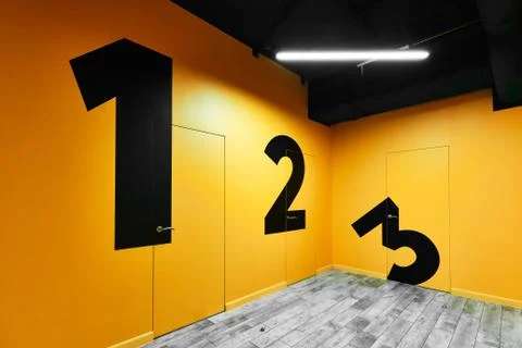 Large numbers from one to three on yellow walls in a room with doors Stock Photos