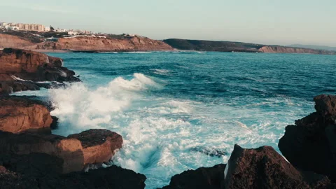 Large ocean waves crash against the rocky shore during sunset. Scenic view of Stock Footage 197376593