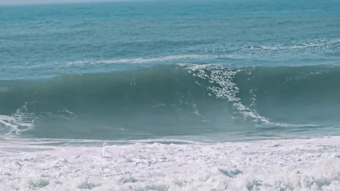 Large ocean waves crashing onto a sandy beach, dramatic coastal landscape 動画素材 347061963