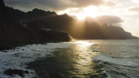Large ocean waves roll on the rocky shore foaming white foam. Mountain range in Stock Footage 220807560