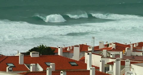 Large ocean waves roll onto a shore lined with white residential buildings with Stock Footage 220786085