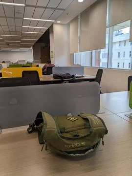 A large office space with a green backpack on a desk. Stock Photos