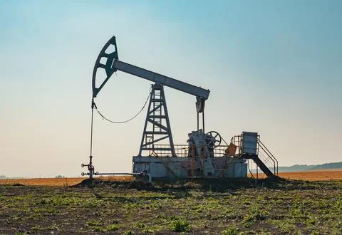 A large oil pump jack operates in an open field, extracting crude oil Stock Photos