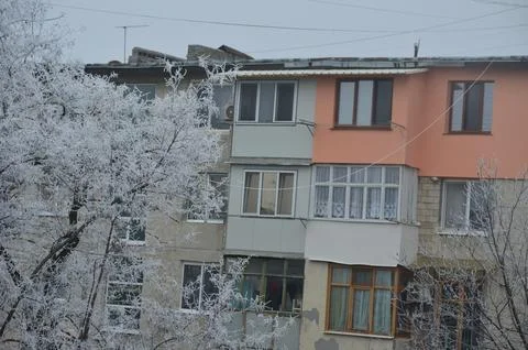 A large, old building with many windows is covered in snow. Stock Photos