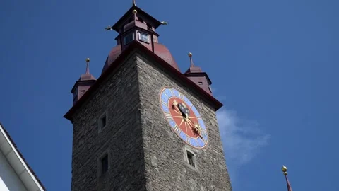 A large old city tower with a red, blue, and gold clock on the side. Video stock 313328119