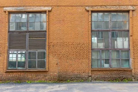 Large old dilapidated red brick house with large dilapidated windows. An old  Stock Photos