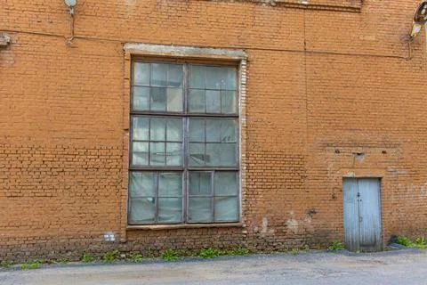 A large old dilapidated red brick house with a large dilapidated window and a Stockfoto's