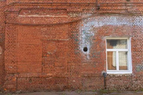 Large old dilapidated red brick house with a white window. Old dirty abandone Stock Photos