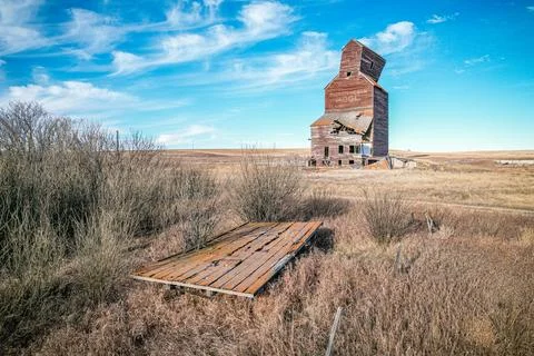 A large, old grain elevator sits in a field Stock Photos