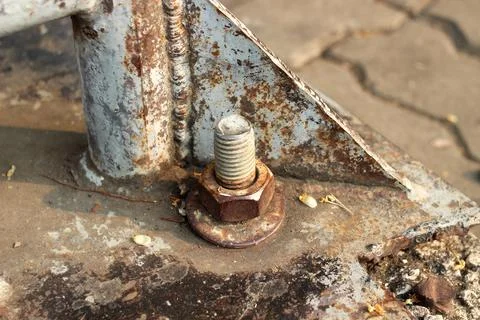 A large, old, rusted nut attached to the steel base structure. Stock Photos