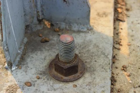 A large, old, rusted nut attached to the steel base structure. Stock Photos