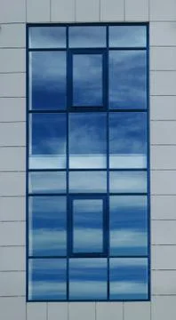 Large opaque window with a reflection of a blue sky Stock Photos