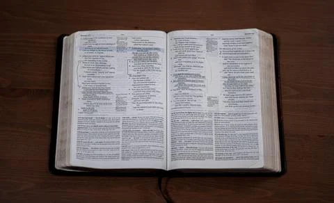 Large open Bible with notes laying on a dark wooden table Stock Photos