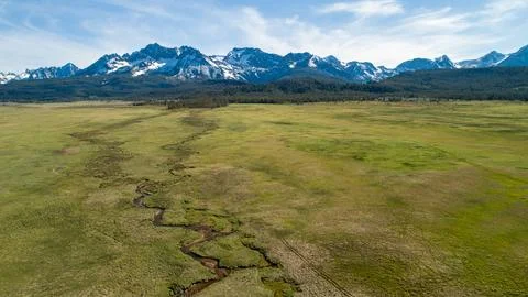 A large, open field with a river running through it Stock Photos