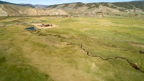 A large, open field with a river running through it Stock Photos