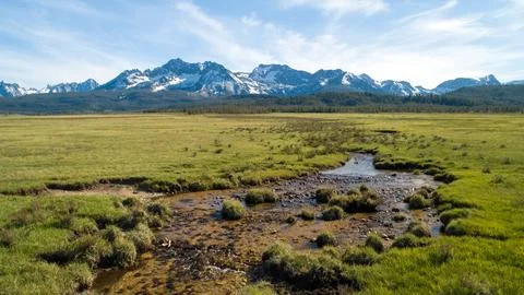 A large, open field with a stream running through it Stock Photos
