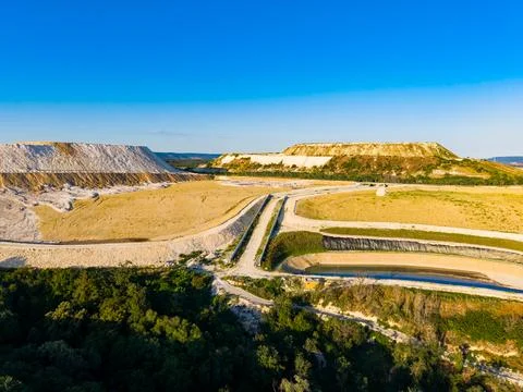Large open mining site shows soil and machinery under blue sky in a rural a.. Stock Photos