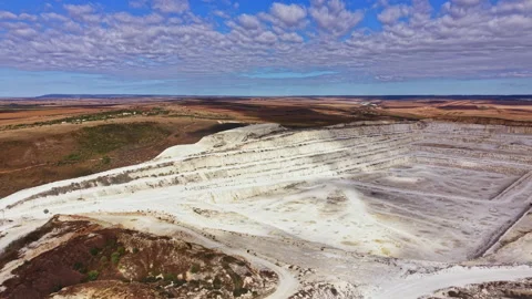Large open-pit mine showing layers of earth and rock with blue sky and clouds in Stock Footage 345455202