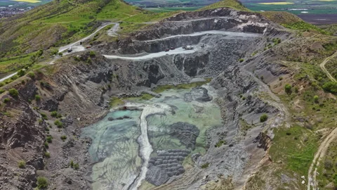 Large open pit mining site located in a hilly area with water accumulation in Stock Footage 342478231