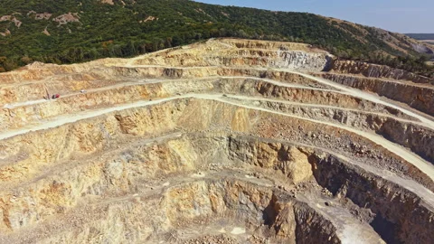 Large open pit mining site located in a hilly area with layers of earth exposed Stock Footage 344095549