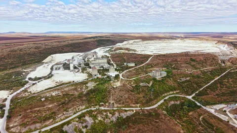 Large open-pit mining site showing machinery, structures, and land in a remote Stock Footage 345455633