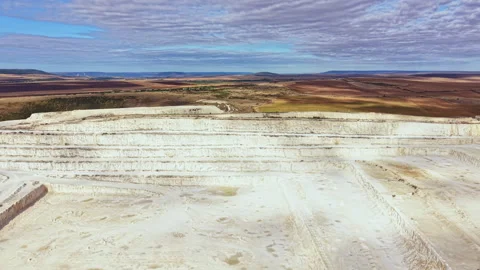 Large open quarry showing white rock layers and a wide landscape with distant Stock Footage 345457277