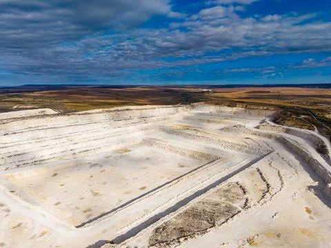 Large open quarry site with layered rock formations in a rural landscape un.. Stock Photos