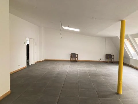 A large, open room with square floor tiles and a small window The room has .. Foto stock