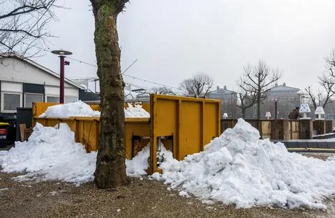 Large orange bin below a tree filled with residual artificial snow Stock Photos