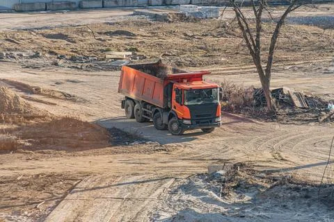 Large orange construction dump truck in industrial setting Stock Photos
