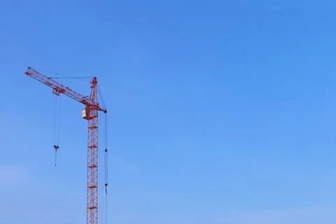Large orange crane without cargo on blue clear sky background Stock Photos