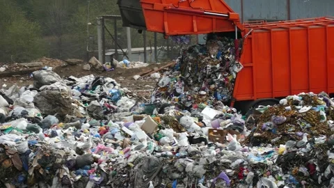A large orange garbage truck dumps garbage at a dump. Stock Footage 315297090