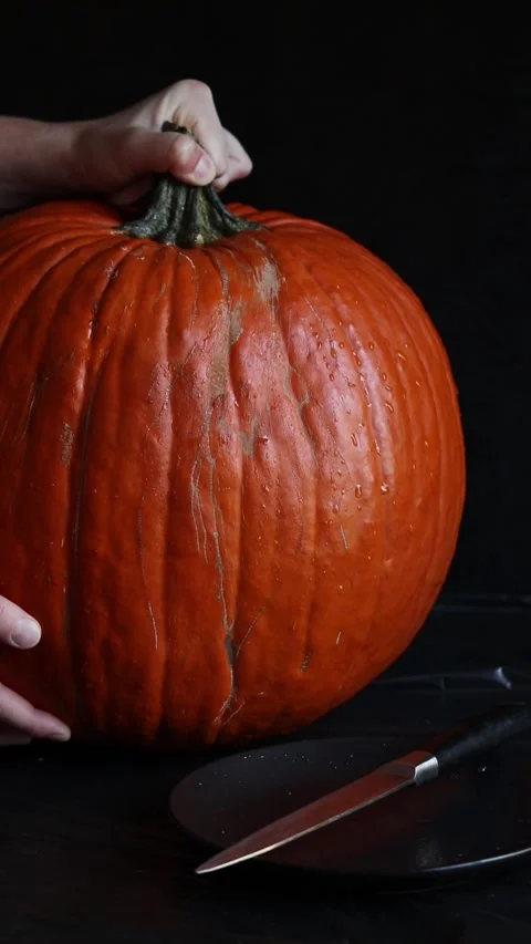 Large orange pumpkin with kitchen knife on dark background 1 Video stock 347586004