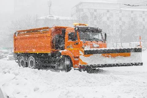 A large orange snowplow stands on the road before snow removal. Special Stock Photos