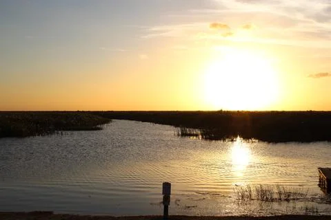 Large orange sun setting in the water Stock Photos