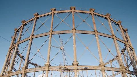 A large ornate rusting Victorian gas holder at gasworks in urban East London Stock Footage 128917784