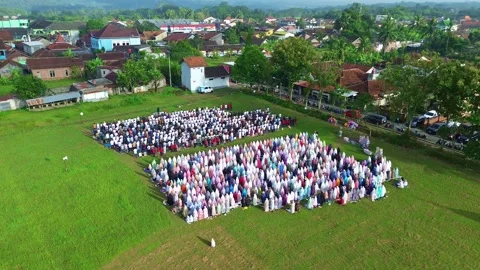 Large outdoor Eid prayer congregation, Muslims praying in rows on green field Stock Footage 335977581