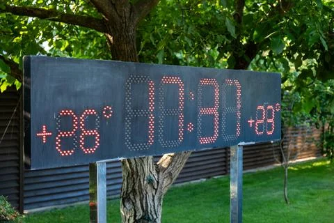 Large outdoor led panel showing current temperature and time in a green garde Stock Photos