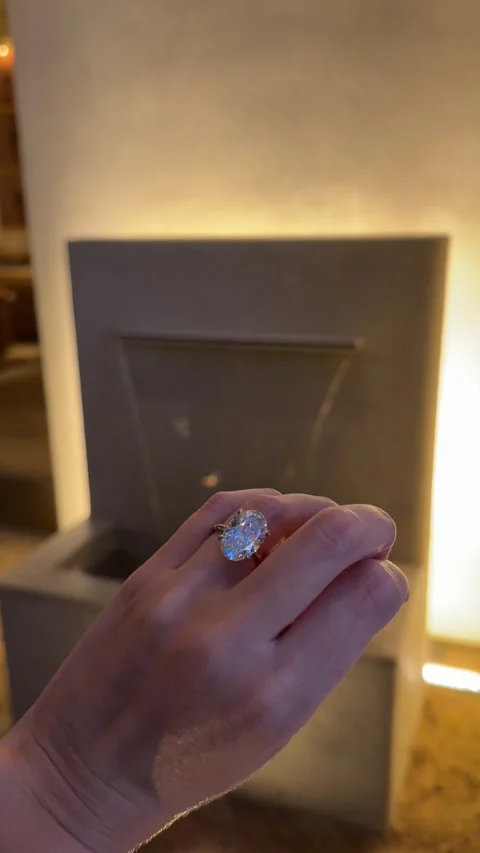 Large oval diamond solitaire engagement ring on hand beside stone fountain 스톡 동영상 325876554