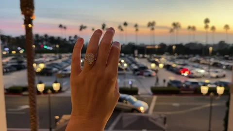 Large oval diamond solitaire engagement ring on hand above busy road Stock Footage 325876558