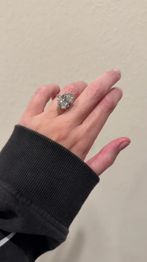 Large oval diamond solitaire engagement ring glittering on hand clean backdrop Stock Footage 325876971