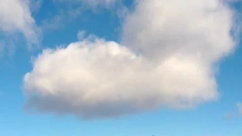 A large overhanging white cloud on a white-on-blue sky approaching below Stock Footage 256647891