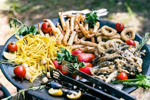 Large pan containing various appetizing seafood dishes, french fries, and Stock Photos