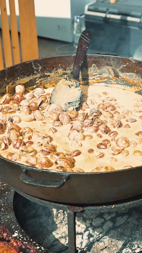 A large pan is placed over an open flame, filled with cooking ingredients that Stock Footage 345886682